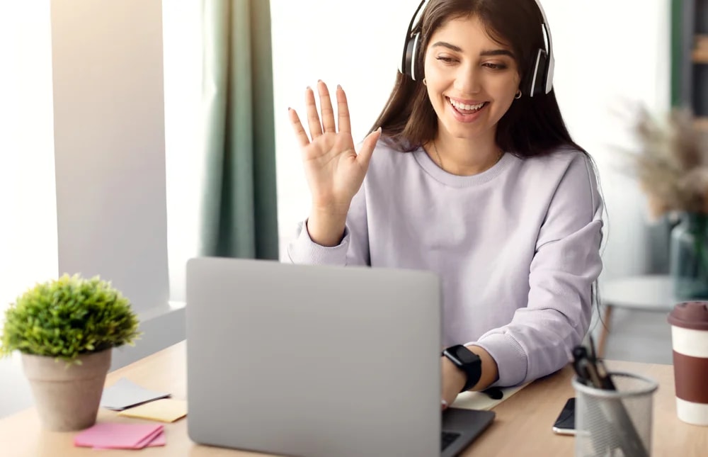 Operadora saludando en una videollamada de onboarding con su laptop